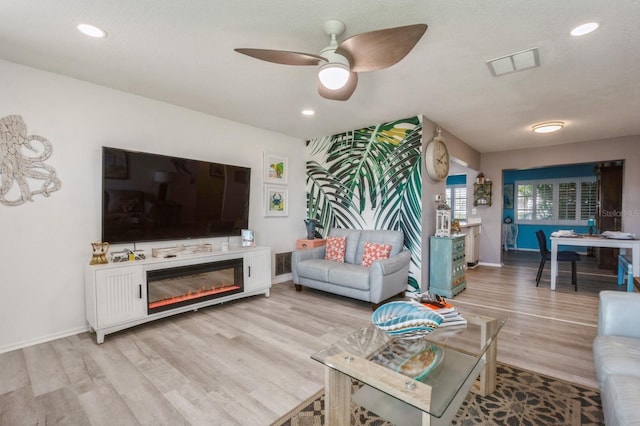 living room with baseboards, visible vents, and light wood finished floors