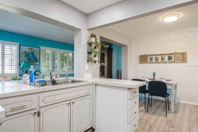 kitchen featuring a textured ceiling, light countertops, a sink, and light wood-style flooring