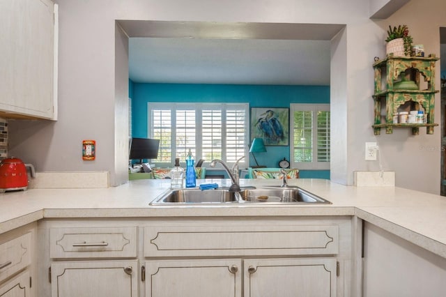 kitchen featuring light countertops, a peninsula, and a sink