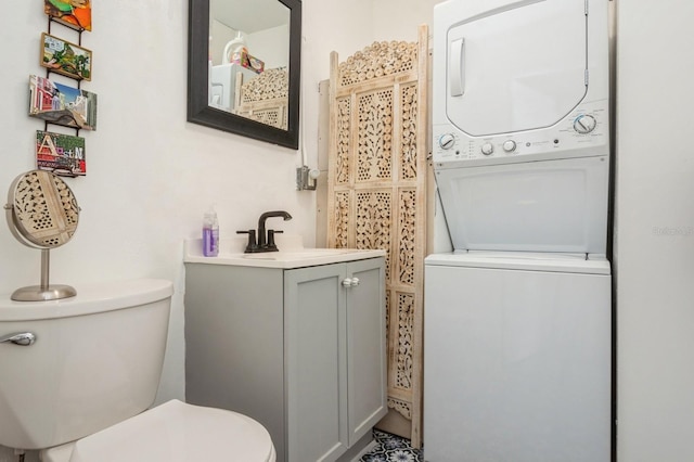 bathroom featuring toilet, vanity, and stacked washer and clothes dryer