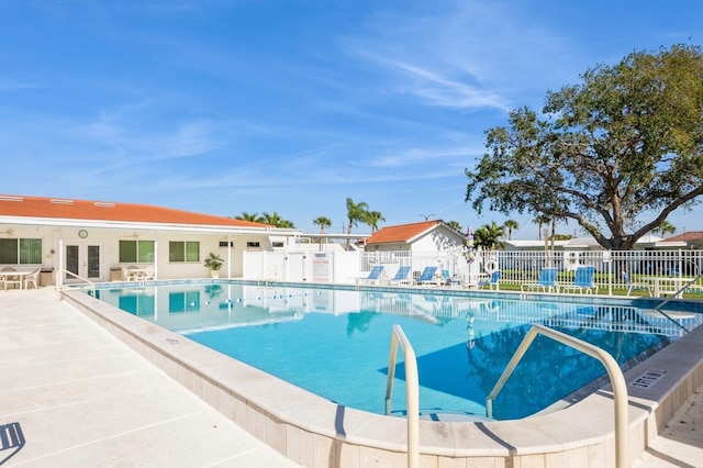 pool with a patio, french doors, and fence