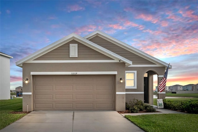 view of front of house featuring stucco siding, a front yard, a garage, and driveway