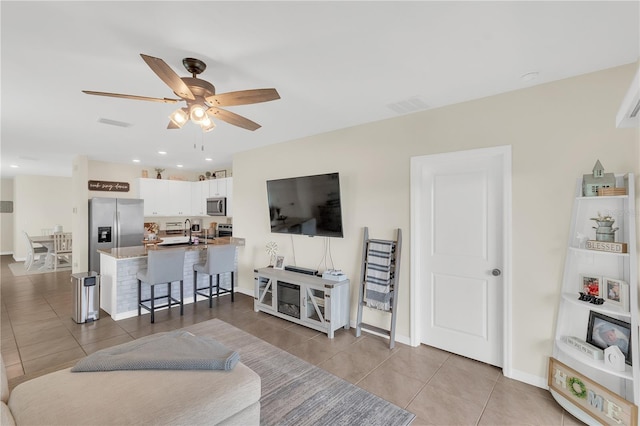 living area with visible vents, baseboards, ceiling fan, and tile patterned flooring