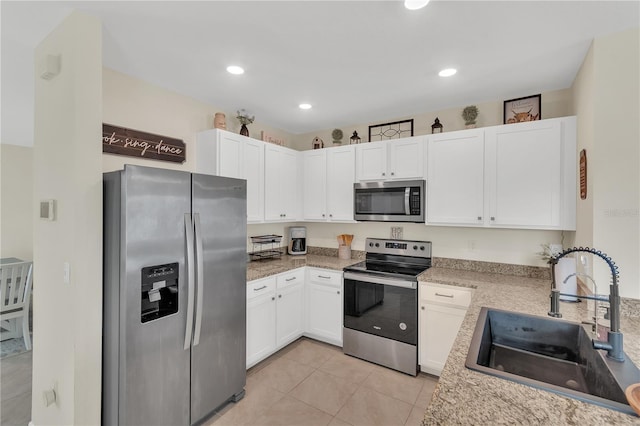 kitchen with light tile patterned floors, recessed lighting, a sink, stainless steel appliances, and white cabinets