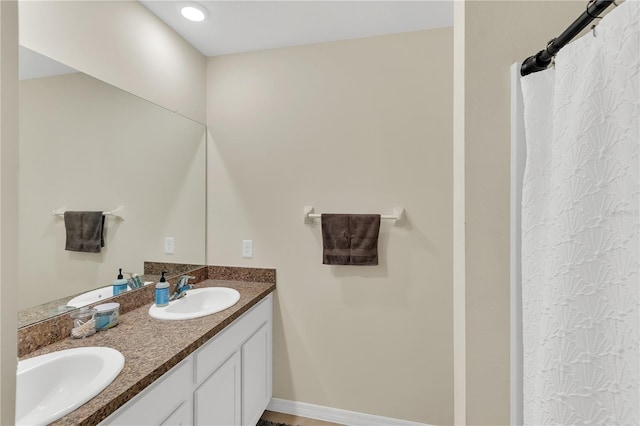 bathroom featuring a sink, baseboards, and double vanity