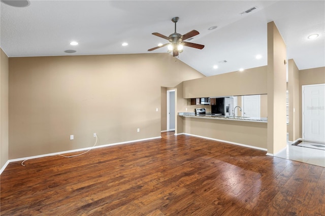 unfurnished living room featuring a sink, ceiling fan, baseboards, and wood finished floors