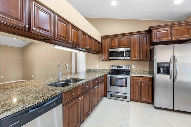 kitchen with stainless steel appliances, light stone counters, a peninsula, and a sink