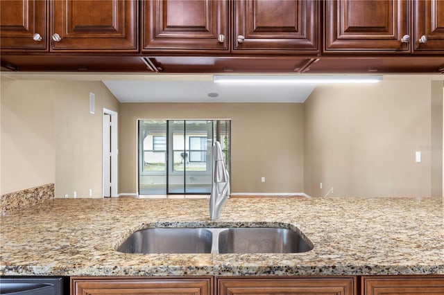 kitchen featuring light stone countertops, a sink, and dishwasher