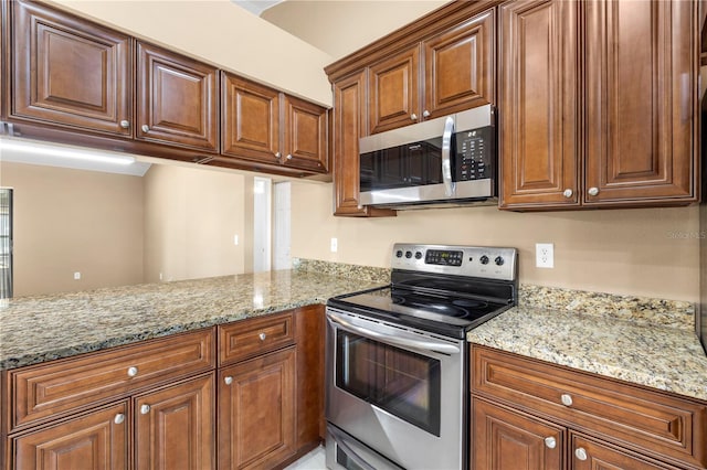 kitchen featuring a peninsula, appliances with stainless steel finishes, light stone counters, and brown cabinets