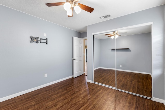 unfurnished bedroom featuring a closet, visible vents, dark wood-type flooring, a ceiling fan, and baseboards