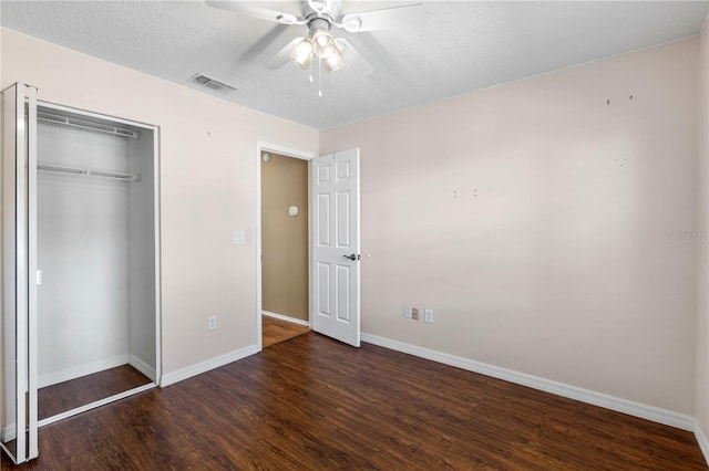 unfurnished bedroom featuring baseboards, visible vents, dark wood-style floors, ceiling fan, and a closet