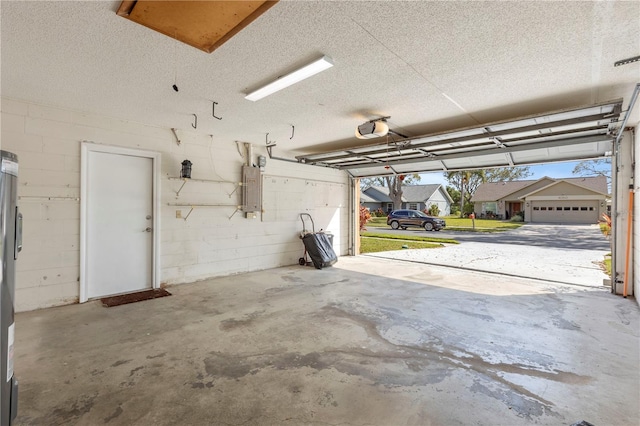 garage featuring electric panel, concrete block wall, a residential view, and a garage door opener