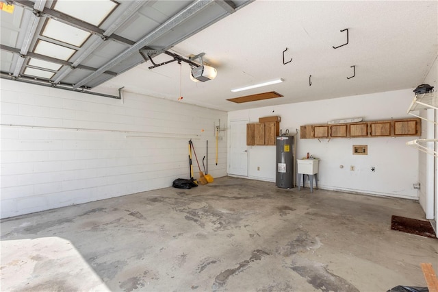 garage featuring water heater, a sink, concrete block wall, and a garage door opener