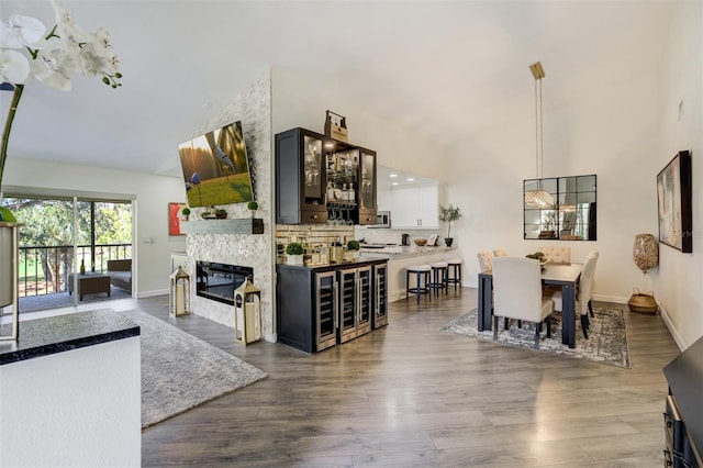 interior space featuring dark wood-style floors, baseboards, a fireplace, and high vaulted ceiling