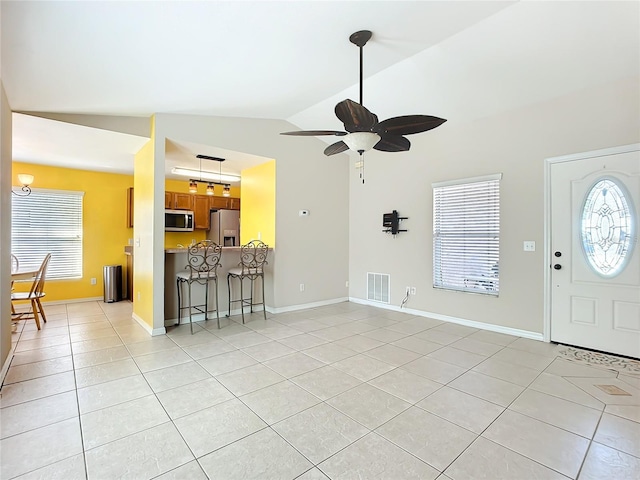 entryway featuring light tile patterned floors, visible vents, baseboards, ceiling fan, and vaulted ceiling