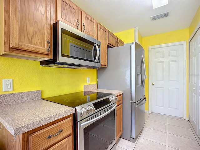 kitchen featuring light countertops, visible vents, appliances with stainless steel finishes, brown cabinetry, and light tile patterned flooring