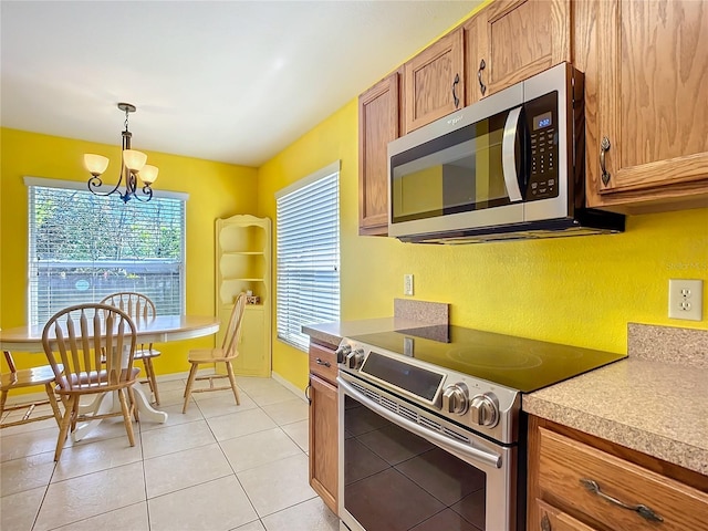 kitchen with hanging light fixtures, light tile patterned floors, appliances with stainless steel finishes, and brown cabinets