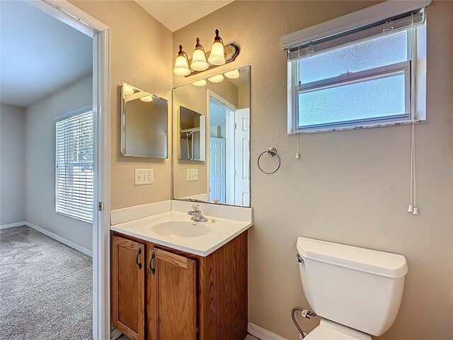 bathroom with a wealth of natural light, baseboards, vanity, and toilet