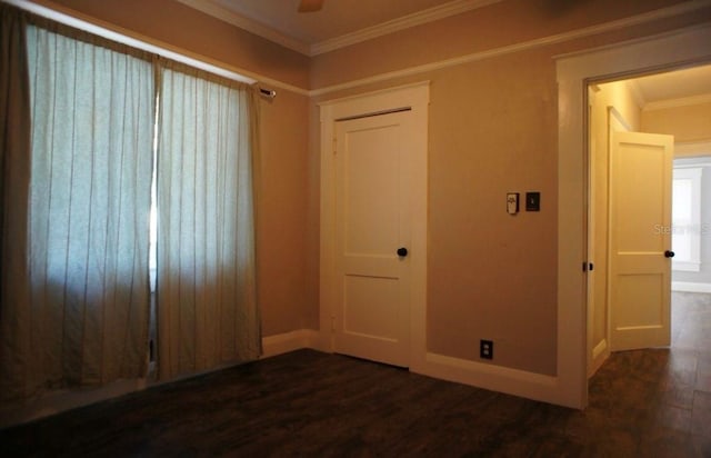 unfurnished room featuring ornamental molding, baseboards, and dark wood-style floors