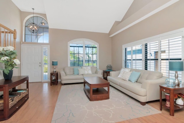 living area featuring a chandelier, high vaulted ceiling, and wood finished floors