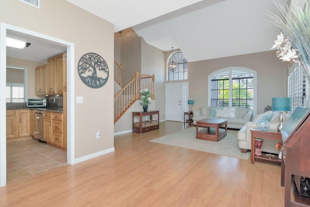 living area with stairs, light wood finished floors, and plenty of natural light