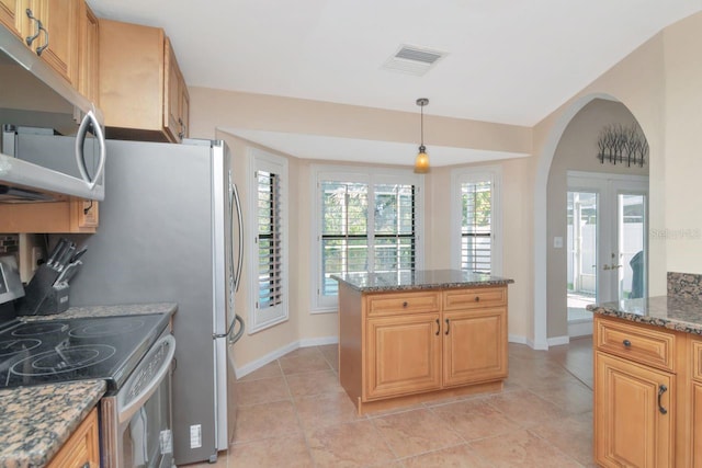 kitchen with arched walkways, stainless steel appliances, visible vents, dark stone counters, and pendant lighting