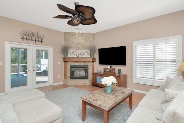 living room with a large fireplace, baseboards, wood finished floors, and french doors