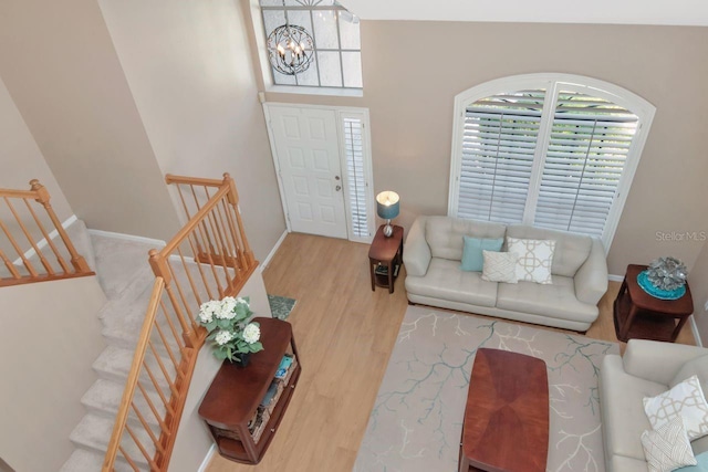 living room featuring stairs, an inviting chandelier, and wood finished floors