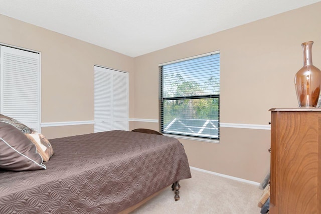 bedroom with multiple closets, carpet flooring, and baseboards