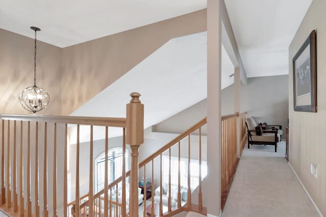 hallway featuring an inviting chandelier, baseboards, carpet flooring, and an upstairs landing