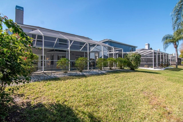 rear view of property featuring glass enclosure, a lawn, and a chimney