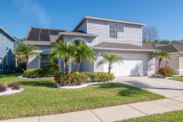 view of front of house featuring a garage, concrete driveway, solar panels, a front yard, and brick siding