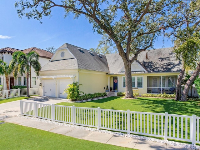 view of front of house with concrete driveway, a fenced front yard, an attached garage, a front lawn, and stucco siding