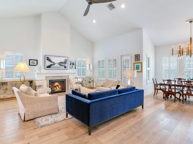 living area featuring light wood-type flooring, plenty of natural light, visible vents, and a glass covered fireplace