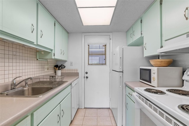 kitchen with white appliances, light tile patterned floors, decorative backsplash, light countertops, and a sink