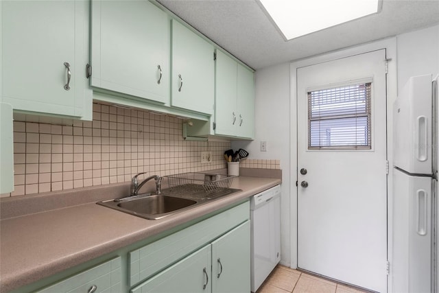 kitchen with light tile patterned floors, white appliances, a sink, light countertops, and decorative backsplash