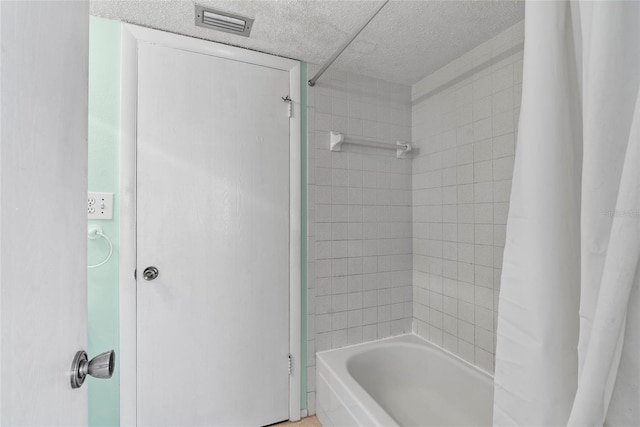 bathroom featuring a textured ceiling, shower / bath combination with curtain, and visible vents