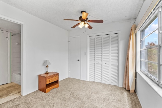 bedroom with a textured ceiling, ceiling fan, ensuite bathroom, light colored carpet, and a closet