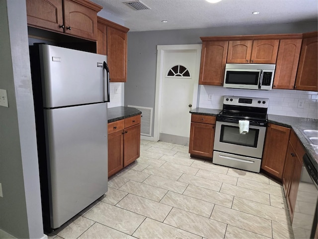 kitchen featuring dark countertops, visible vents, stainless steel appliances, and decorative backsplash