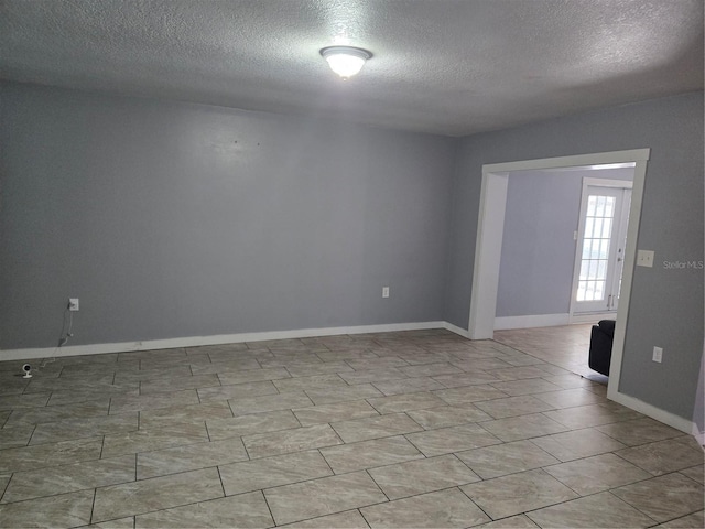 spare room featuring baseboards and a textured ceiling