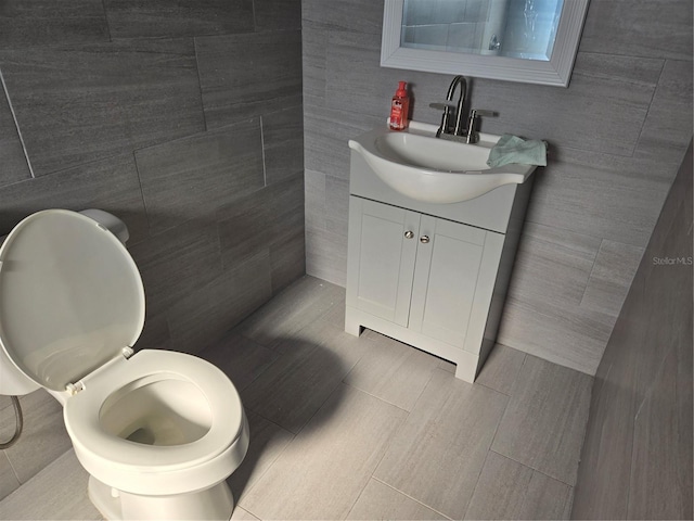 bathroom featuring tile walls, vanity, and toilet