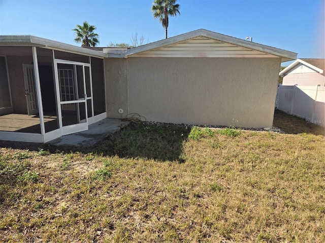 view of side of property featuring a yard, fence, and a sunroom