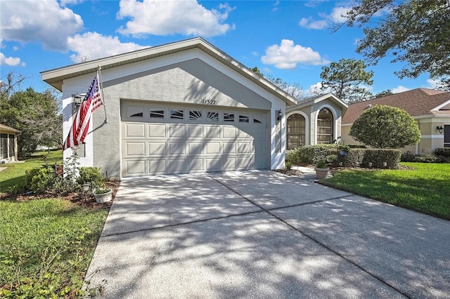 ranch-style home featuring a garage, driveway, a front lawn, and stucco siding