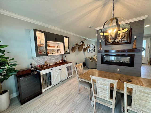 kitchen with decorative light fixtures, ornamental molding, decorative backsplash, a glass covered fireplace, and glass insert cabinets