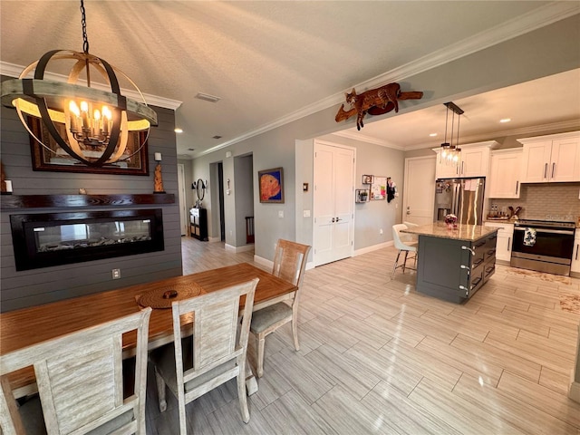 kitchen with white cabinets, a kitchen island, light stone counters, hanging light fixtures, and stainless steel appliances