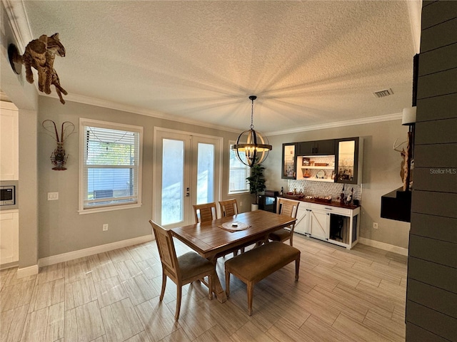 dining area featuring french doors, crown molding, light wood finished floors, visible vents, and a textured ceiling