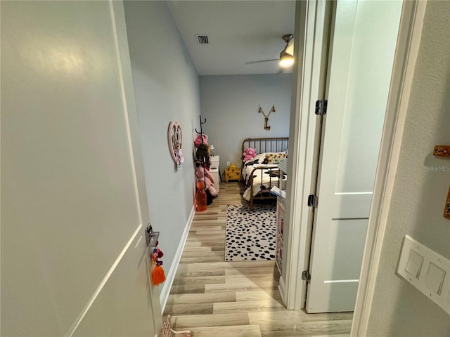 corridor featuring baseboards, visible vents, and light wood finished floors