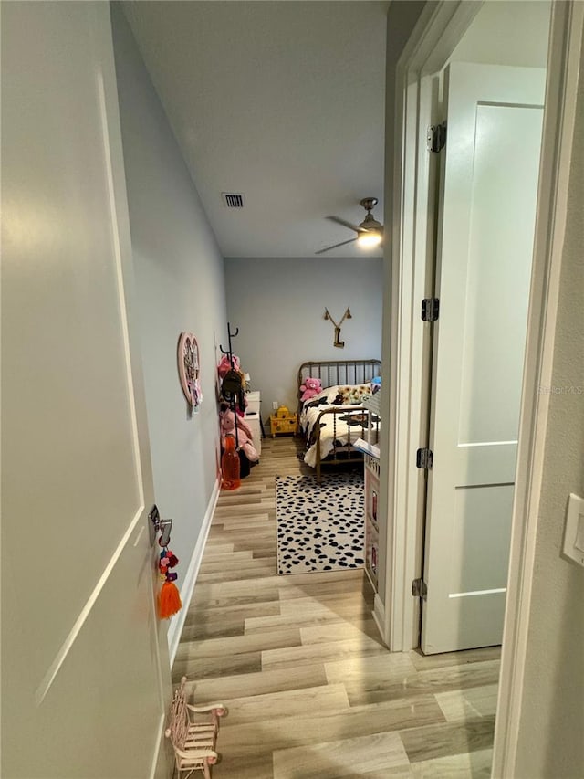 hall with light wood finished floors, visible vents, and baseboards