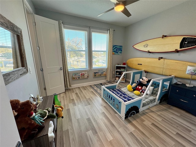 bedroom featuring light wood-style floors, baseboards, and a ceiling fan