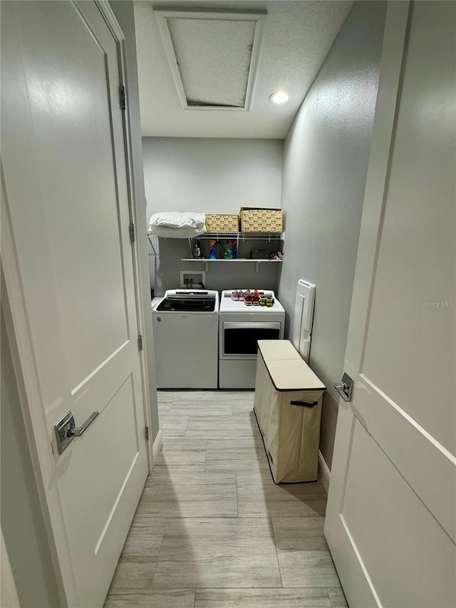 clothes washing area with laundry area, separate washer and dryer, and attic access